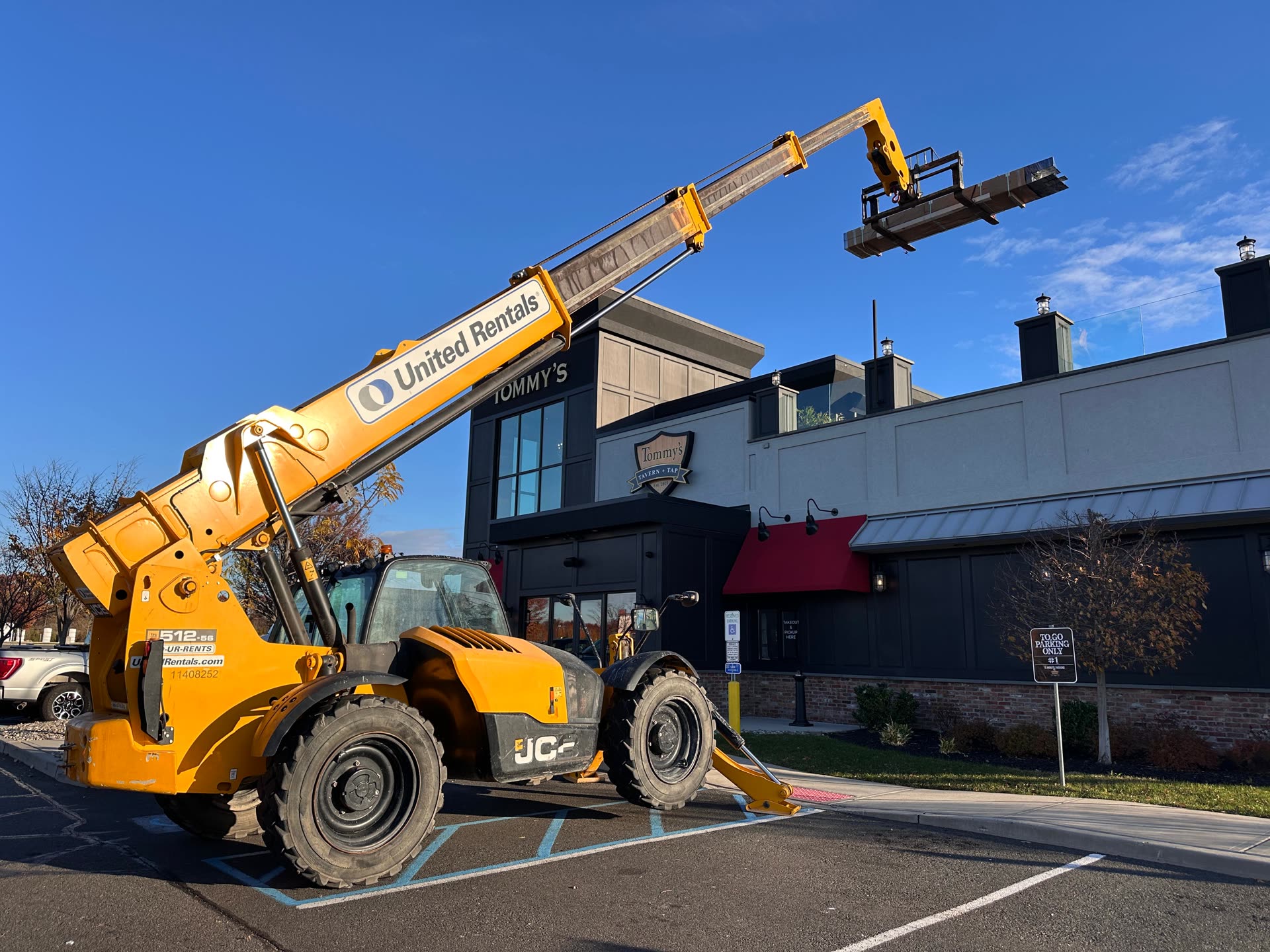 JCB telehandler crane lifting steel structural materials up to the roof of Tommy's Tavern & Tap Edison during louvered roof installation