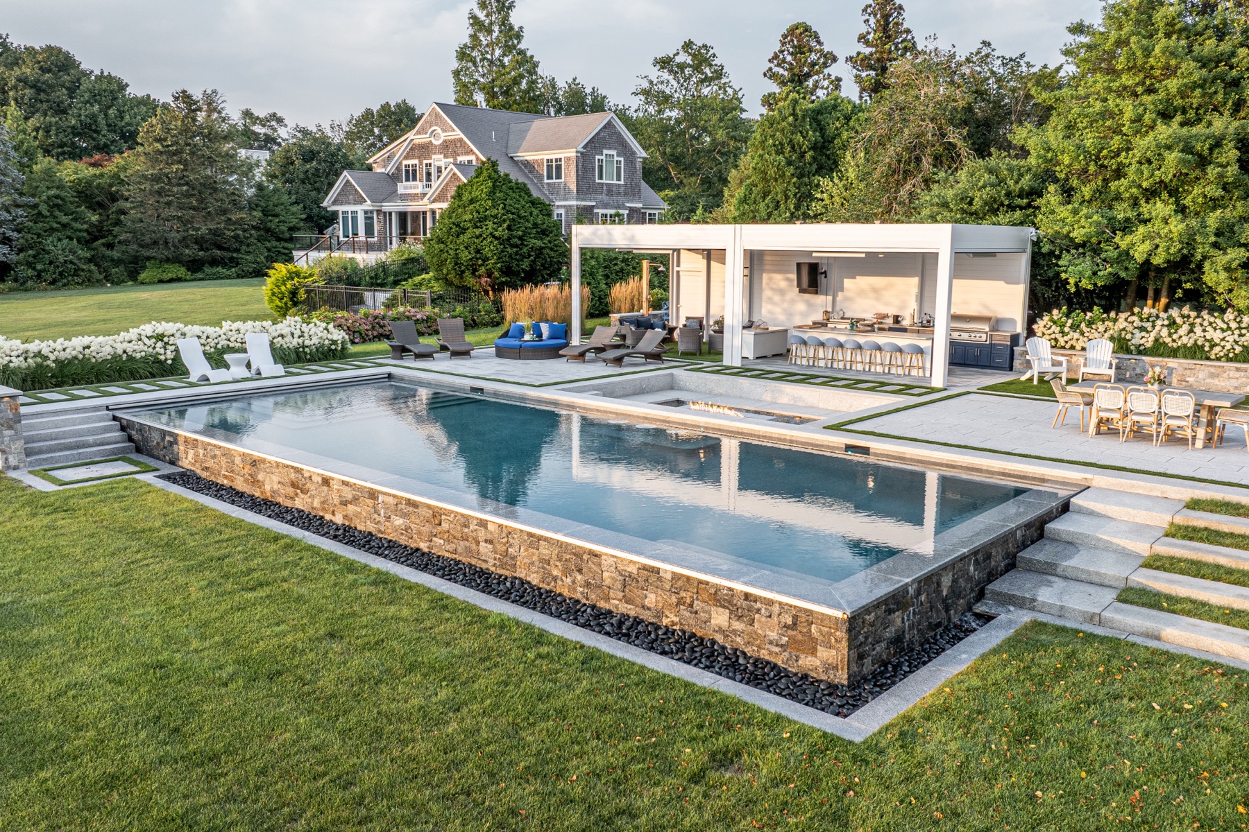Daytime aerial — louvered pergola, bar and infinity-edge pool with stone surround