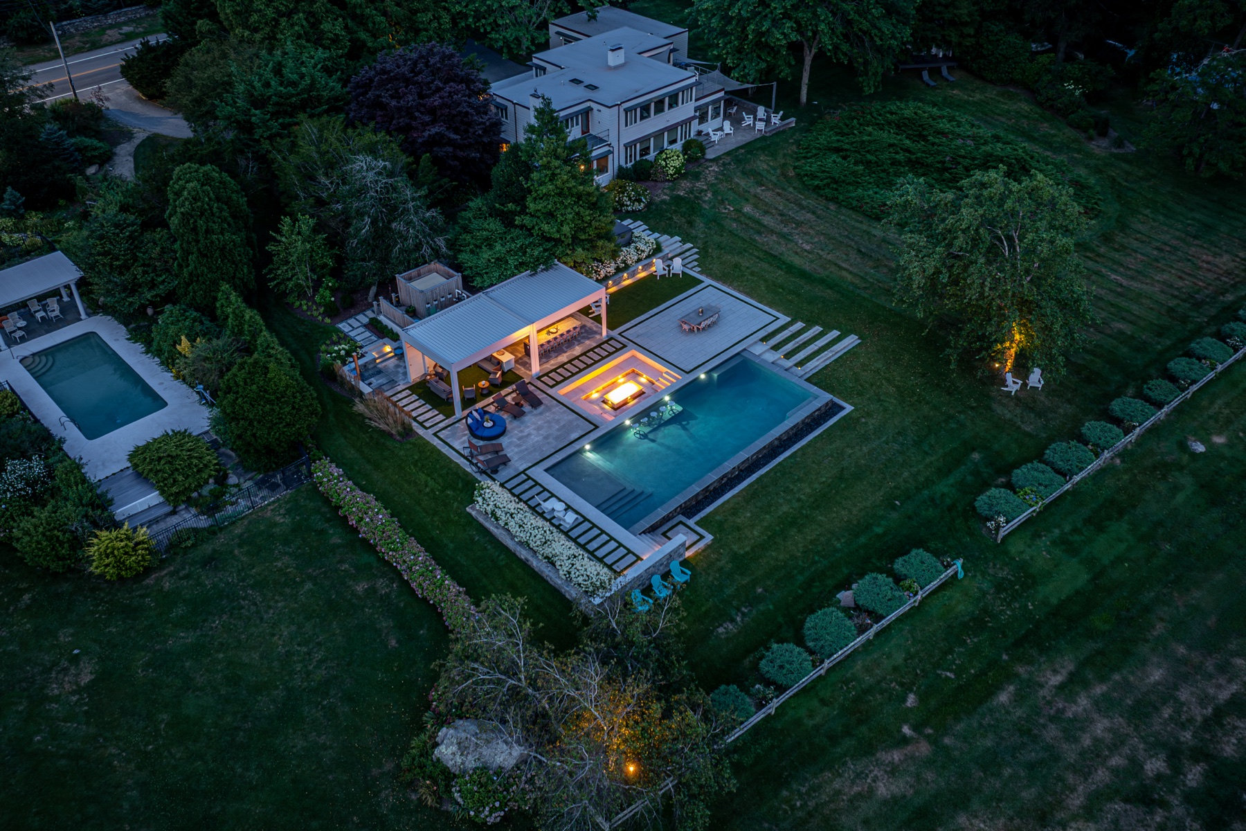 Twilight aerial of the full estate — louvered pergola, pool and spa