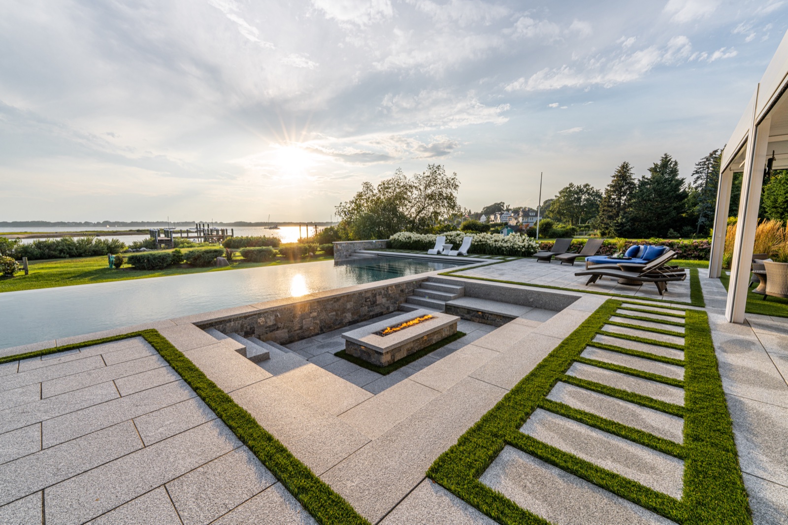 Sunset over the bay — infinity-edge pool and fire feature on the bluestone terrace